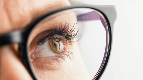 Ojo femenino reflexivo con gafas
 - Foto, Imagen