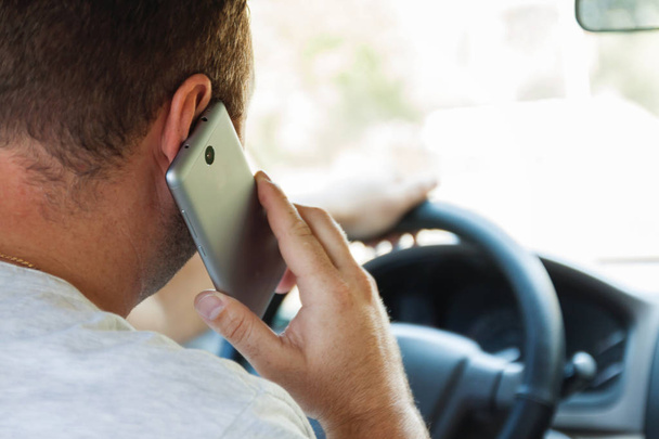 man talking on a cell phone while driving a car - Fotó, kép
