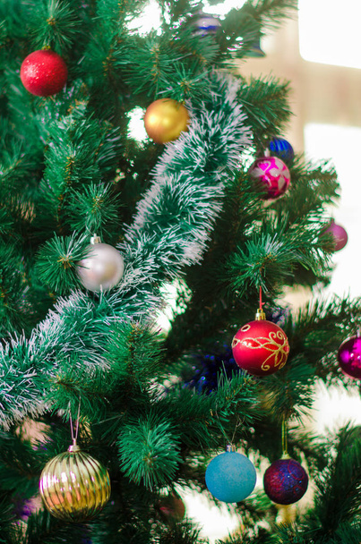 Closeup της κόκκινο μπιχλιμπίδι κρέμεται από ένα στολισμένο χριστουγεννιάτικο δέντρο - Φωτογραφία, εικόνα