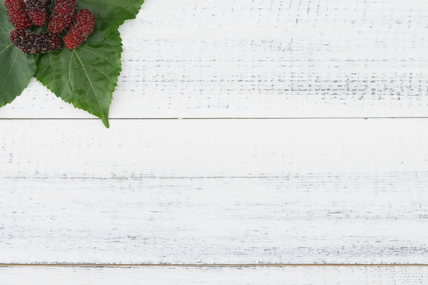 Mulberries and leaves on white wood background  - Photo, Image
