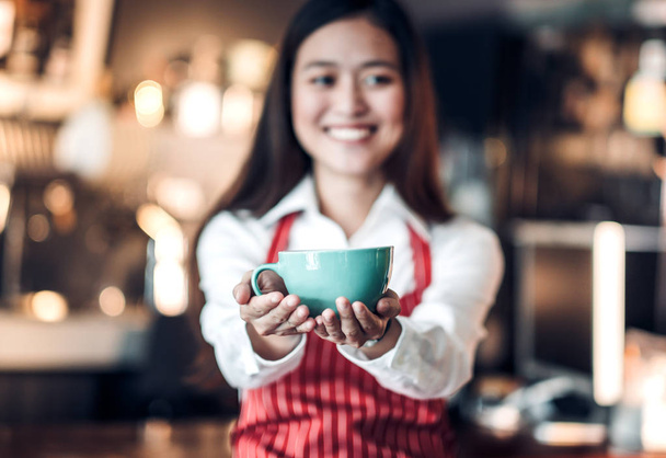 Close up on coffee up with blur asian woman barista holding mug  - Foto, Bild