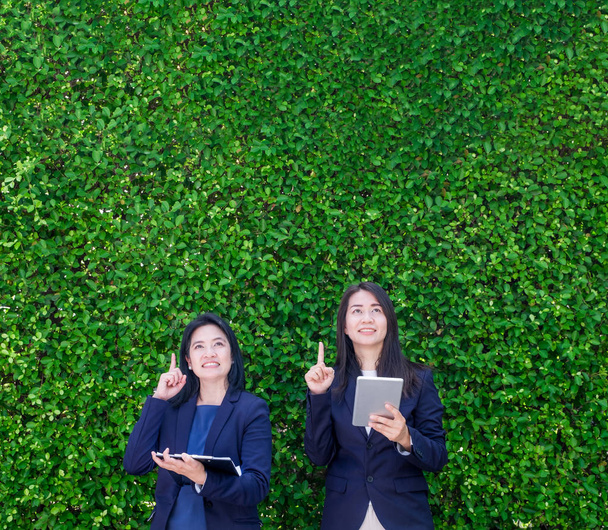 Two Asian businesswoman holding tablet and point finger up to ai - Foto, Bild