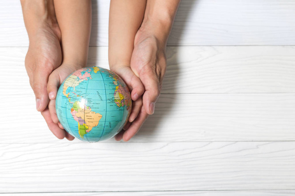 Conceito mundial: Duas mãos humanas segurando global em backgrou de madeira
 - Foto, Imagem