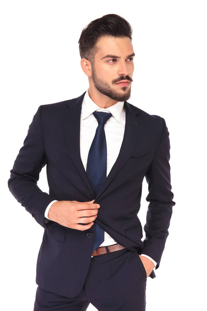 Seitenansicht eines jungen Geschäftsmannes, der sich seinen Anzug zuknöpft  - Foto, Bild