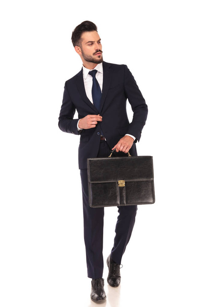 young business man walking with briefcase and looks to side  - Foto, afbeelding
