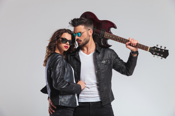 cool punk hombre sosteniendo la guitarra en el hombro y abrazando a la mujer
  - Foto, Imagen