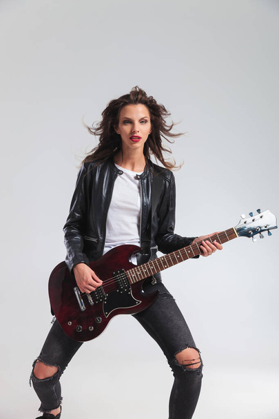 young woman in leather jacket playing electric guitar  - Foto, afbeelding