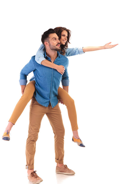 side view of a young happy casual couple presenting - Photo, Image