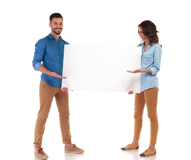 happy young casual couple presenting big blank board  - Foto, afbeelding