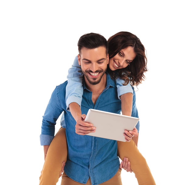 joven pareja casual riendo mientras leen juntos en una tableta
 - Foto, imagen