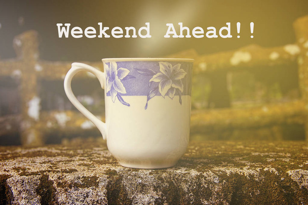 Кофейная чашка на каменном столе со словом "Weekend Ahead"
" - Фото, изображение