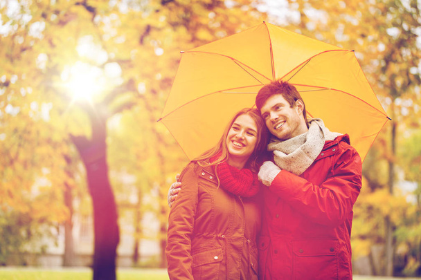 smiling couple with umbrella in autumn park - Foto, Bild