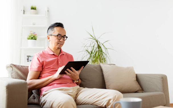 man with tablet pc sitting on sofa at home - Photo, Image