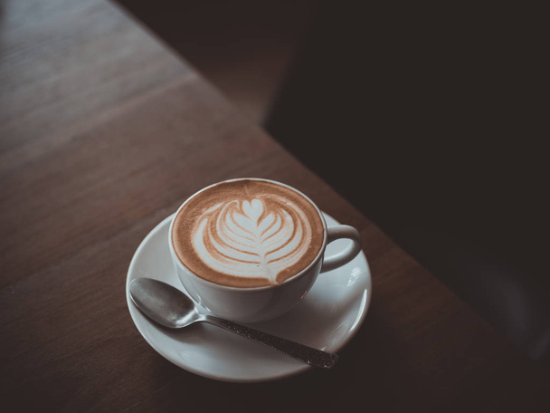 φλιτζάνι καφέ latte τέχνη στον ξύλινο γραφείο κατάστημα καφέ καφέ vintage χρωματικό τόνο - Φωτογραφία, εικόνα