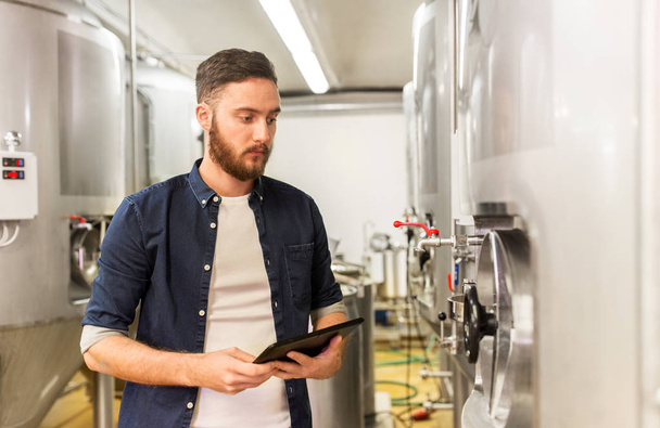 man with tablet pc at craft brewery or beer plant - Foto, immagini