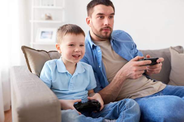 father and son playing video game at home - Foto, Imagem
