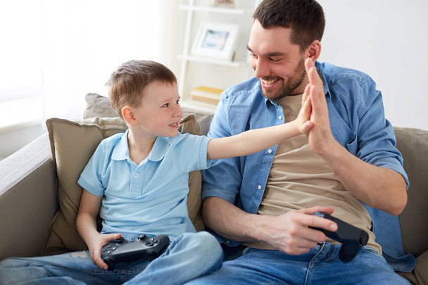 father and son with gamepads doing high five - Valokuva, kuva