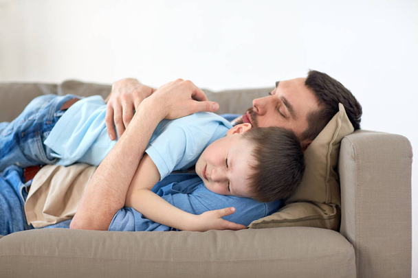 happy father and son sleeping on sofa at home - Foto, Imagem