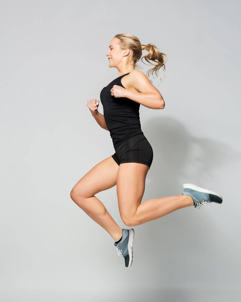 young woman in black sportswear jumping - 写真・画像