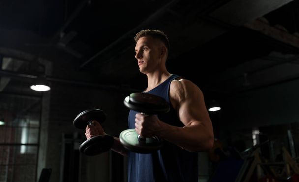 young man with dumbbells exercising in gym - Fotografie, Obrázek
