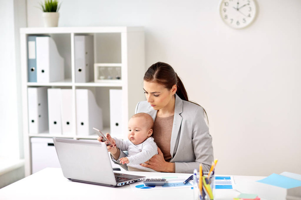 businesswoman with baby and smartphone at office - 写真・画像