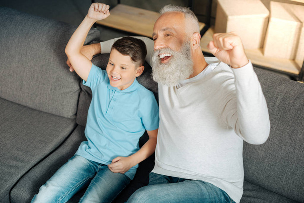 Little boy and his grandfather celebrating victory of favorite team - Photo, Image