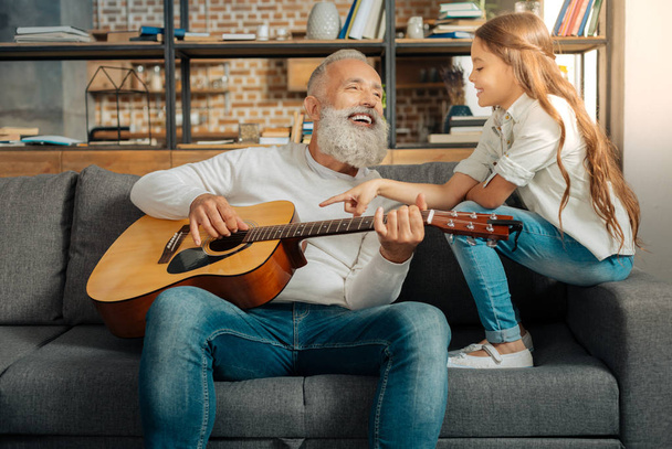 Grandfather chatting with granddaughter while holding guitar - Photo, image