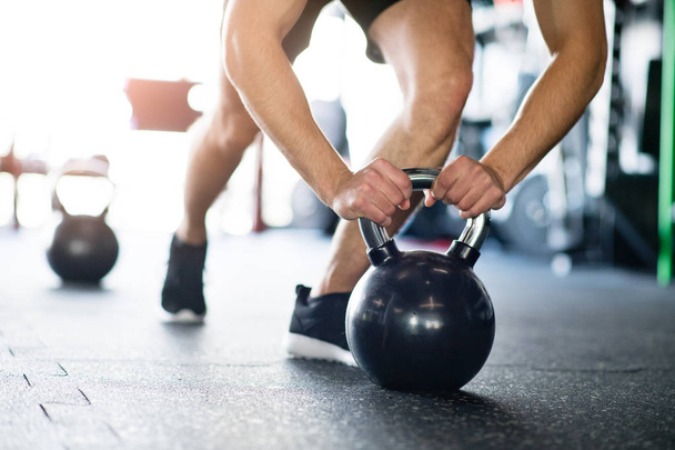 Unrecognizable fit man in gym doing push ups on kettlebells - 写真・画像