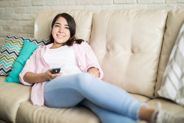Hispanic woman with tv remote - Foto, afbeelding