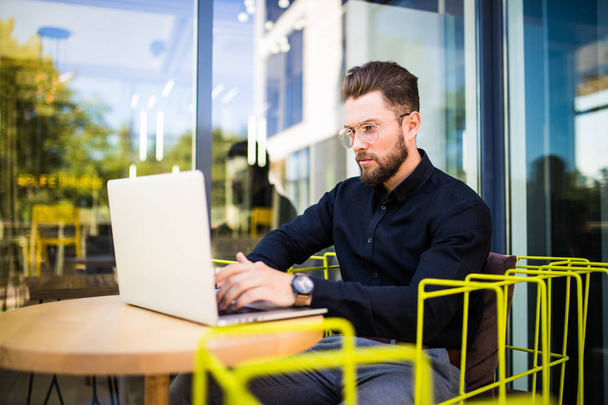Красивий бізнесмен, використовуючи сучасний ноутбук на відкритому повітрі, успішний менеджер, який працює в кафе під час перерви та пошуку інформації в Інтернеті на своєму ноутбуці
 - Фото, зображення