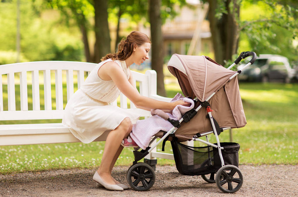 happy mother with child in stroller at summer park - Foto, Imagem