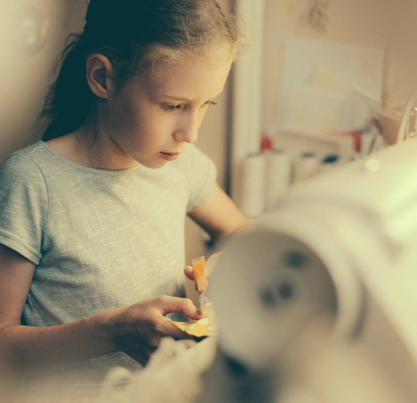 Маленькая девочка работает на швейной машинке дома
. - Фото, изображение