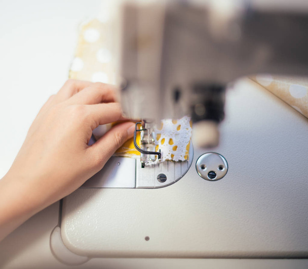 Little girl working on sewing machine at home. Close-up view. - Foto, Imagen