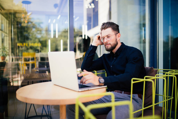 Красивый бизнесмен, пользующийся современным ноутбуком на открытом воздухе, успешный менеджер, работающий в кафе во время перерыва и ищущий информацию в Интернете на своем ноутбуке
 - Фото, изображение