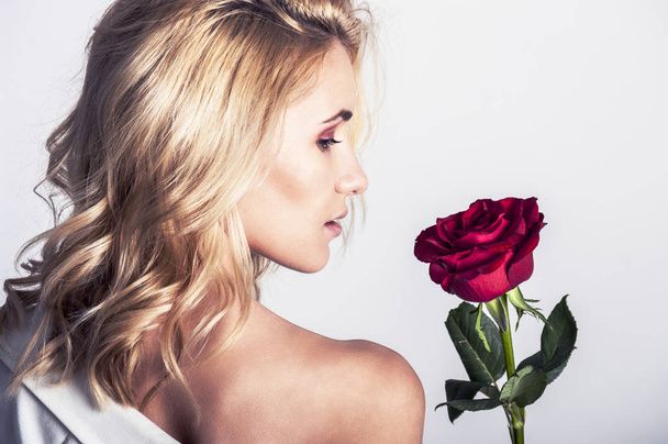 Portret pięknej kobiety blondynka z długie blond włosy, doskonałej skóry, utrzymuje twarz bukiet czerwonych róż kwiatów, zmysłowy i uśmiechając się w dzień kobiet, Walentynki - Zdjęcie, obraz