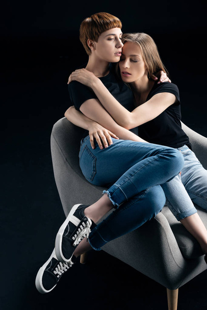 lesbian couple embracing in armchair - Fotografie, Obrázek