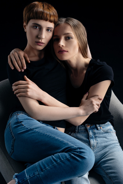 lesbian couple embracing in armchair - 写真・画像