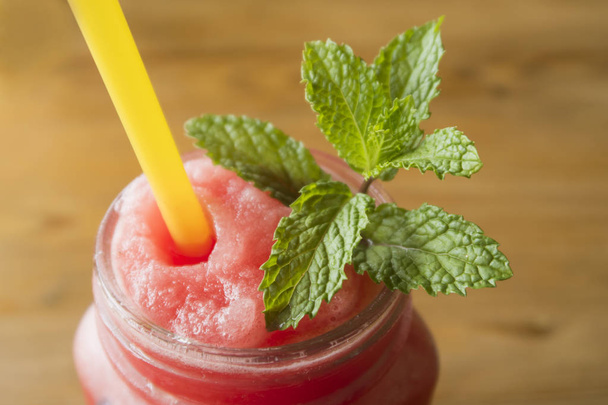 A glass of watermelon juice with mint leaves and yellow straw  - Foto, imagen