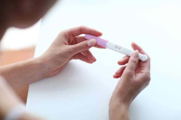 Frau hält Schwangerschaftstest an den Händen. - Foto, Bild