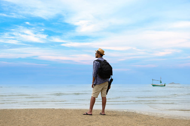 Young traveler man with backpack standing at seaside and looking to the ocean - Photo, Image