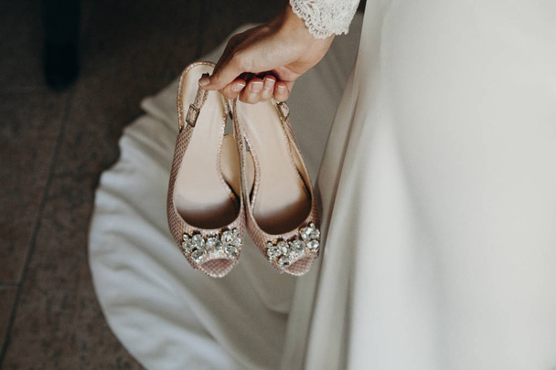 Bride holding a pair of bridal shoes in the hand. - Fotó, kép