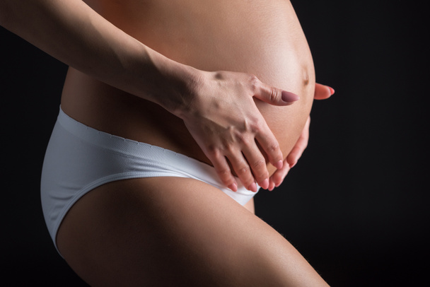 Terhes nő fogdossa a hasát - Fotó, kép