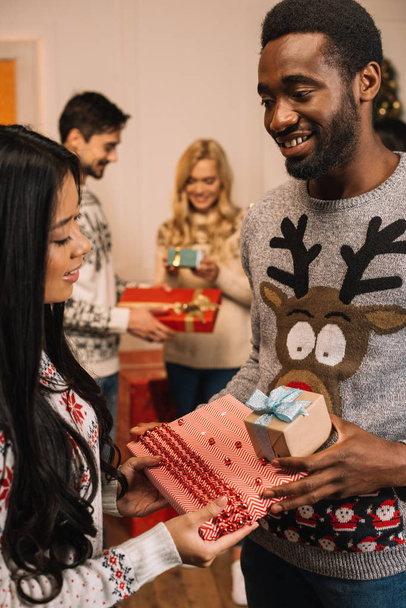 pareja multiétnica intercambiando regalos de Navidad
 - Foto, Imagen