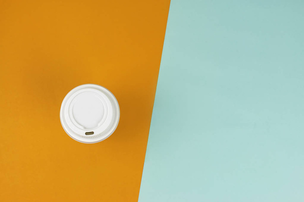 Flat lay of Take out paper coffee cup on blue and orange  - Фото, изображение