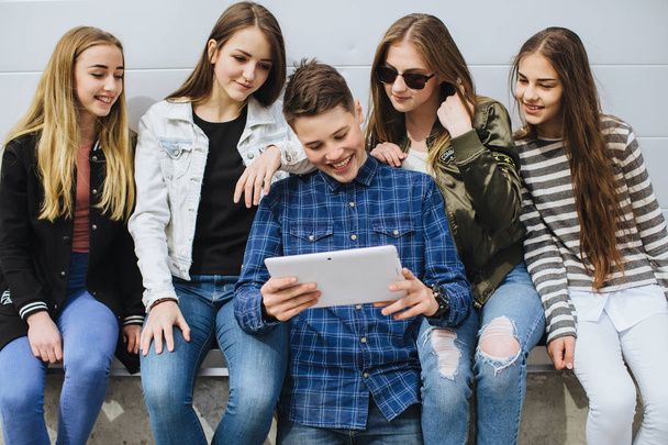 Lächelnde Teenager hängen draußen mit Tablet herum - Foto, Bild