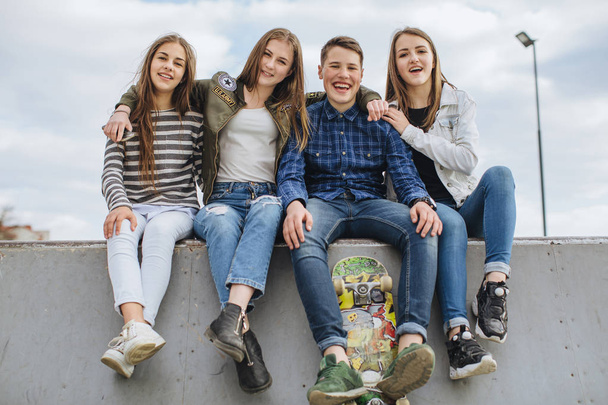 Adolescents souriants avec planche à roulettes traînant dehors
 - Photo, image