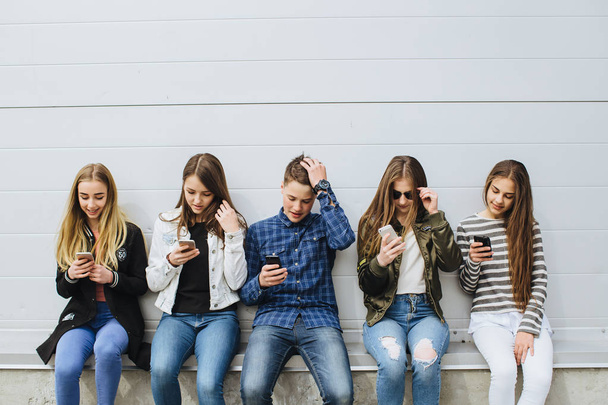 Groep tieners buitenshuis met mobiele telefoons - Foto, afbeelding