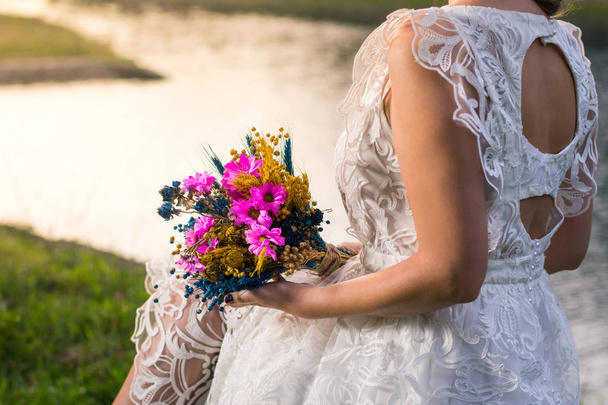 Νύφη κρατώντας γαμήλια ανθοδέσμη από τη λίμνη - Φωτογραφία, εικόνα