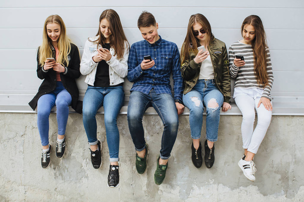 Gruppo di adolescenti all'aperto con telefoni cellulari
 - Foto, immagini