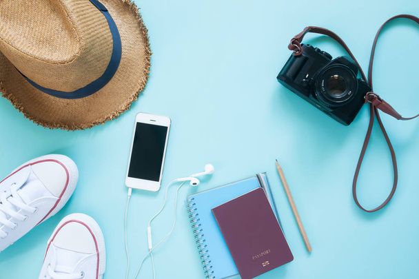 Επίπεδη lay ταξιδιωτικών ειδών με κινητή συσκευή, διαβατήριο και κάμερα παστέλ χρώμα φόντου - Φωτογραφία, εικόνα